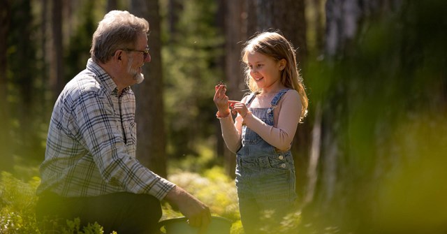 Grandfather and a young granddaughter at a forest. They look happy.