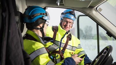 Two Oulun Energia employees in work clothes talking in the doorway of a van.